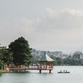 Fukuoka, Japan - A boat and a hexagonal, vermilion pavilion on a large pond at Ohori Park.